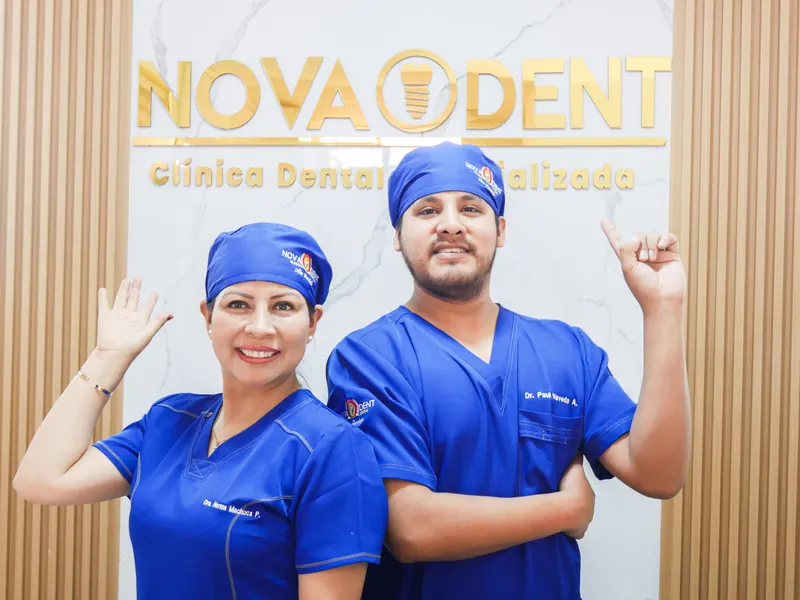 Dos especialistas de Novaodent frente al logotipo de la clínica